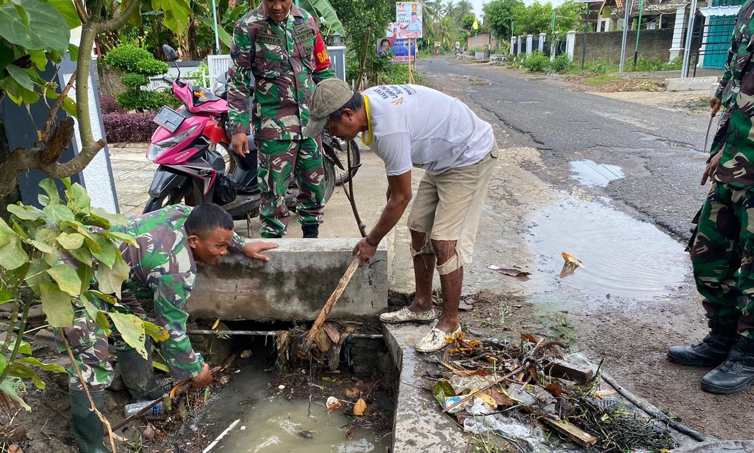 Babinsa Koramil 422-01/Kdd Kodim 0421/Ls bersama warga bersihkan saluran air guna mengantisipasi banjir, Jumat (5/01/2024). (Dok)