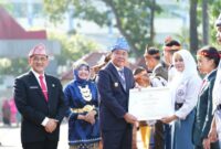 Wakil Gubernur Sumatera Selatan H. Cik Ujang (tengah) didampingi Sekretaris Daerah Sumsel Dr. H. Edward Candra (kiri) menyerahkan Piagam Penghargaan kepada siswi berprestasi pada Upacara Peringatan Hari Pendidikan Nasional (Hardiknas) 2026 di halaman Kantor Pemprov Sumsel, Palembang, Senin (4/5/2026). Momentum Hardiknas tahun ini difokuskan pada penguatan karakter siswa dan penerapan metode pembelajaran mendalam (deep learning) menuju generasi emas. (Foto: Dok/Pemprov Sumsel)