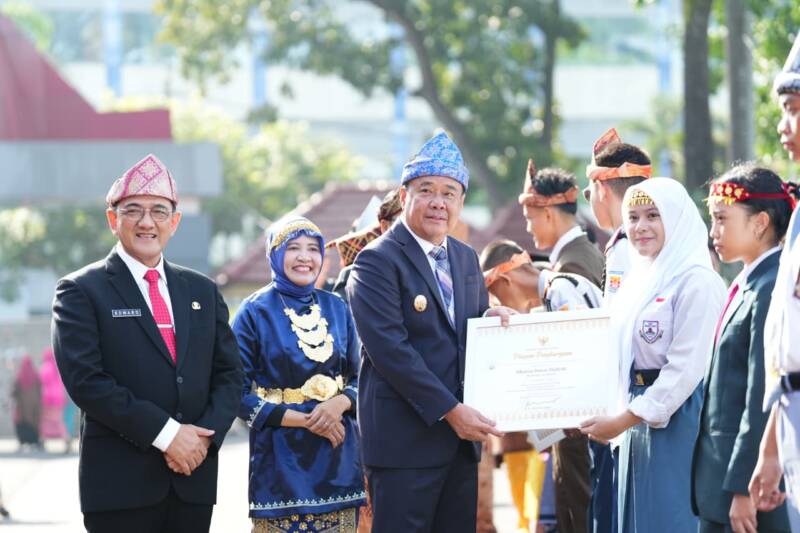 Wakil Gubernur Sumatera Selatan H. Cik Ujang (tengah) didampingi Sekretaris Daerah Sumsel Dr. H. Edward Candra (kiri) menyerahkan Piagam Penghargaan kepada siswi berprestasi pada Upacara Peringatan Hari Pendidikan Nasional (Hardiknas) 2026 di halaman Kantor Pemprov Sumsel, Palembang, Senin (4/5/2026). Momentum Hardiknas tahun ini difokuskan pada penguatan karakter siswa dan penerapan metode pembelajaran mendalam (deep learning) menuju generasi emas. (Foto: Dok/Pemprov Sumsel)