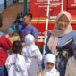 WALAUPUN MEMBELUDAK TETAP AMAN: Seorang ibu, Cika Nabila, bersama anak-anaknya berfoto di depan armada Damkar PALI saat mengantre wahana Flying Fox gratis dalam momen Sunday Morning di Lapangan Sanggar Pramuka Gelora November Pertamina Pendopo, Talang Ubi, Minggu (7/6/2026). Wahana edukasi adrenalin ini sukses menyedot perhatian ratusan warga dengan pengawasan ketat personel Damkar demi menjaga komitmen 'Zero Accident'. (Foto: Dok/tintamerah.co)