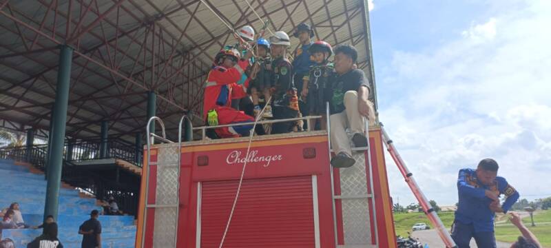 Petugas Damkar PALI dengan sigap memasang tali pengaman (harness) pada anak-anak warga di atas mobil rescue 