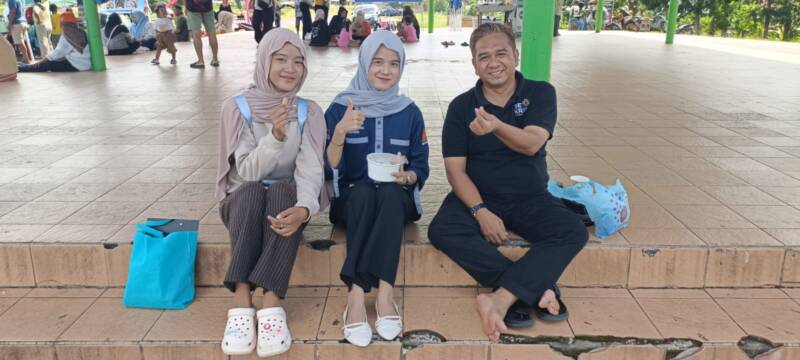 Mahasiswi Akuntansi Universitas IBA Palembang asal Desa Lubuk Tampui, Jessie Widia Yanti (tengah), didampingi rekannya saat mewawancarai dan melakukan pengambilan data kuesioner skripsi berbasis digital kepada pelaku usaha serta Kepala Dinas Koperasi dan UKM Kabupaten PALI, Raden Abdurrohman (kanan), di kawasan kuliner Sunday Morning Lapangan Sanggar Pramuka Gelora November Pertamina Pendopo, Talang Ubi, Minggu (7/6/2026). Riset ini fokus mengkaji literasi keuangan dan pemanfaatan teknologi informasi demi mendorong akuntabilitas laporan keuangan UMKM lokal. (Foto: Dok/tintamerah.co)